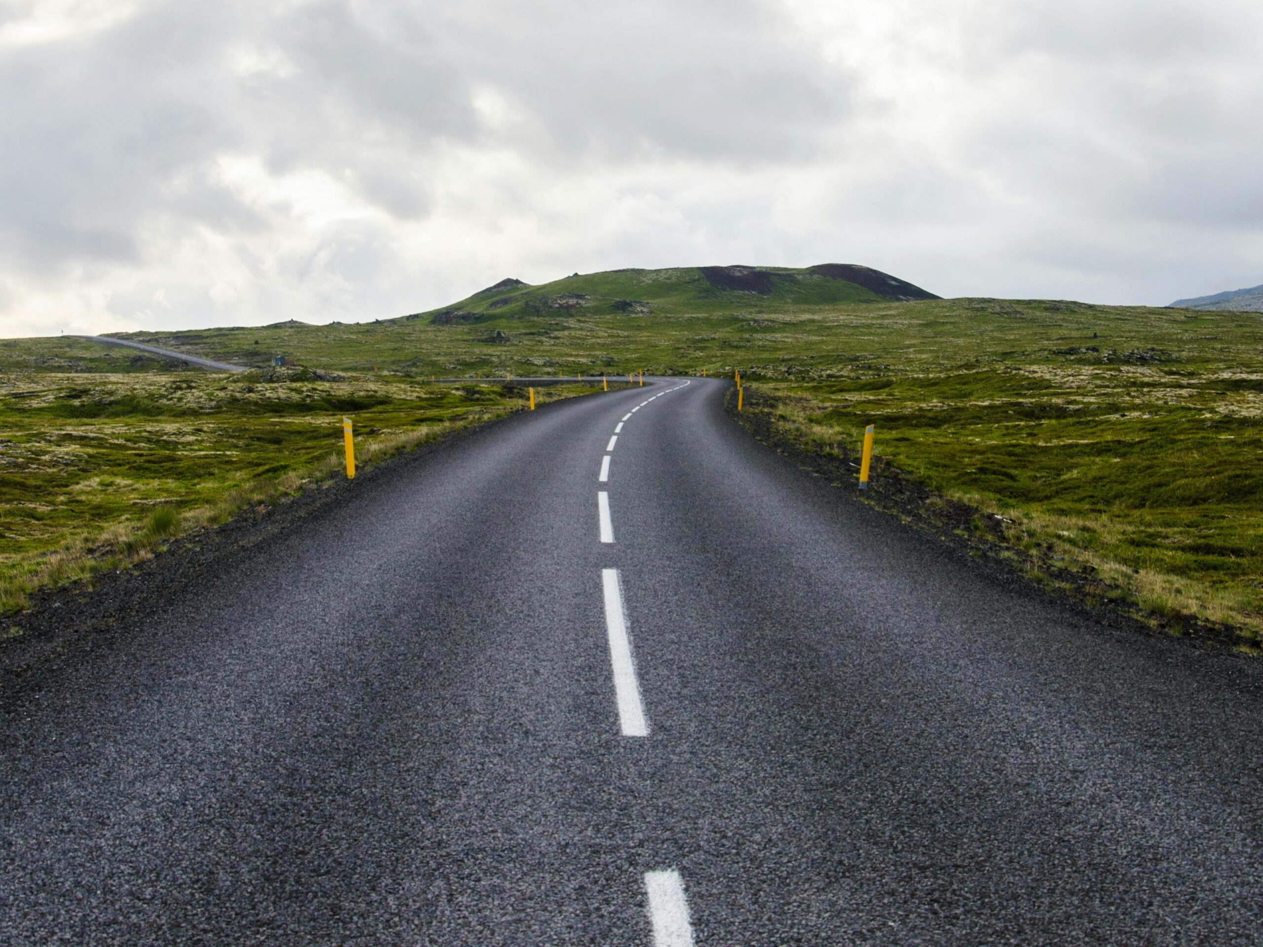 pexels-photo-416974-416974 Empty road stretches through lush countryside under cloudy skies, ideal for travel themes.